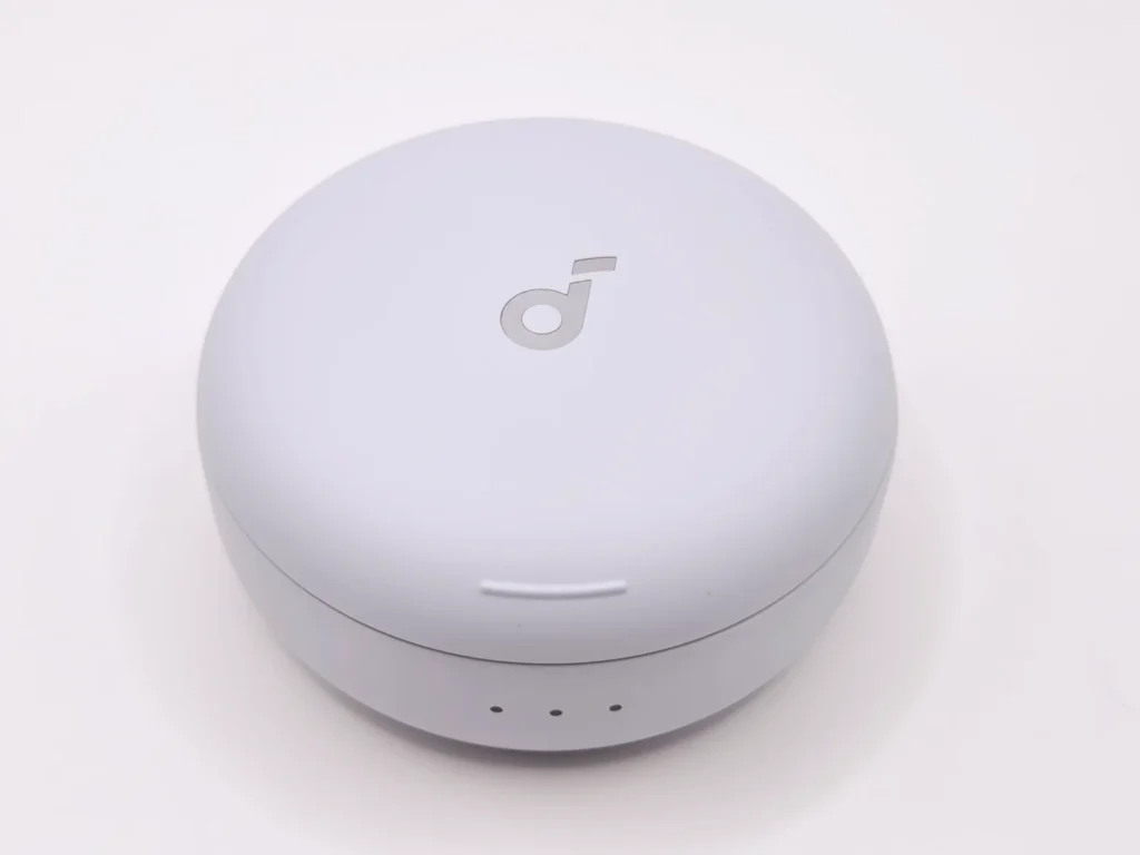 丸くて平たい充電ケースの上面・soundcoreロゴ