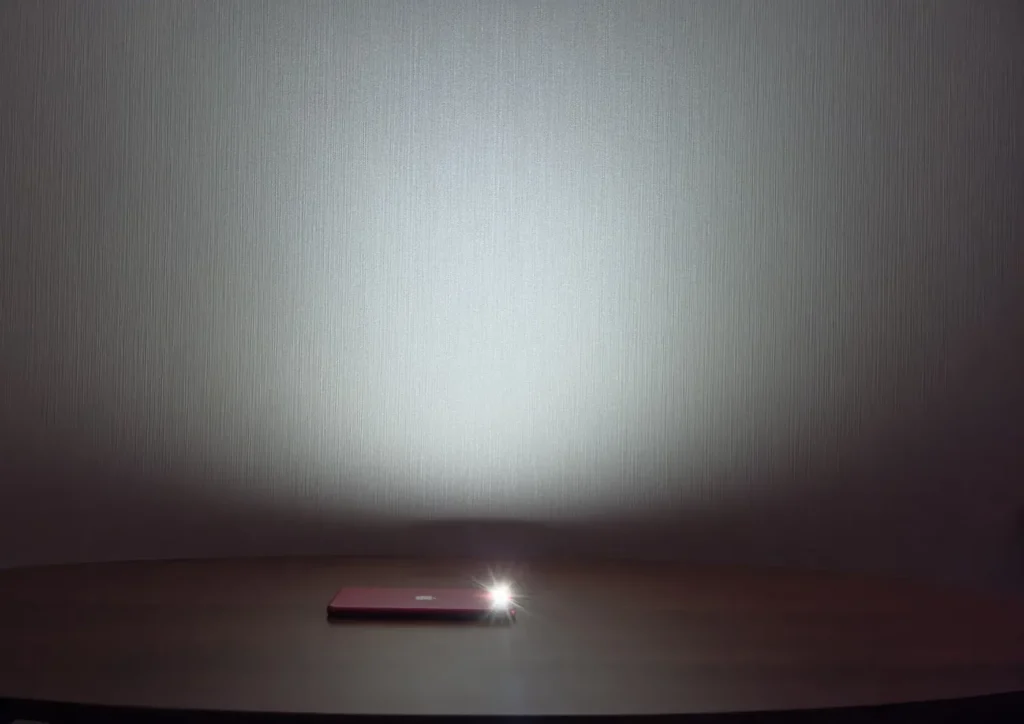 同じ位置でスマホのライトを点けた様子。光は上の壁に向かい、テーブルの上は暗いまま