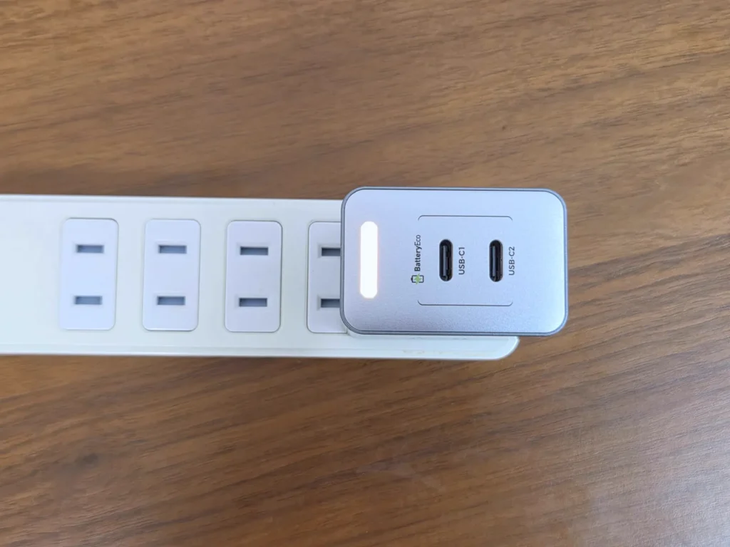 差込口が縦向きの電源タップに挿した PHYSCE 35W 充電器、本体が横向きになり隣の差込口にかかっている